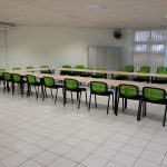 Salle de réunion: ensemble de tables polyvalentes fixées entre elles par des pieds fixes + chaise visiteur assise tapissé tissu noir et dossier filet vert anis
